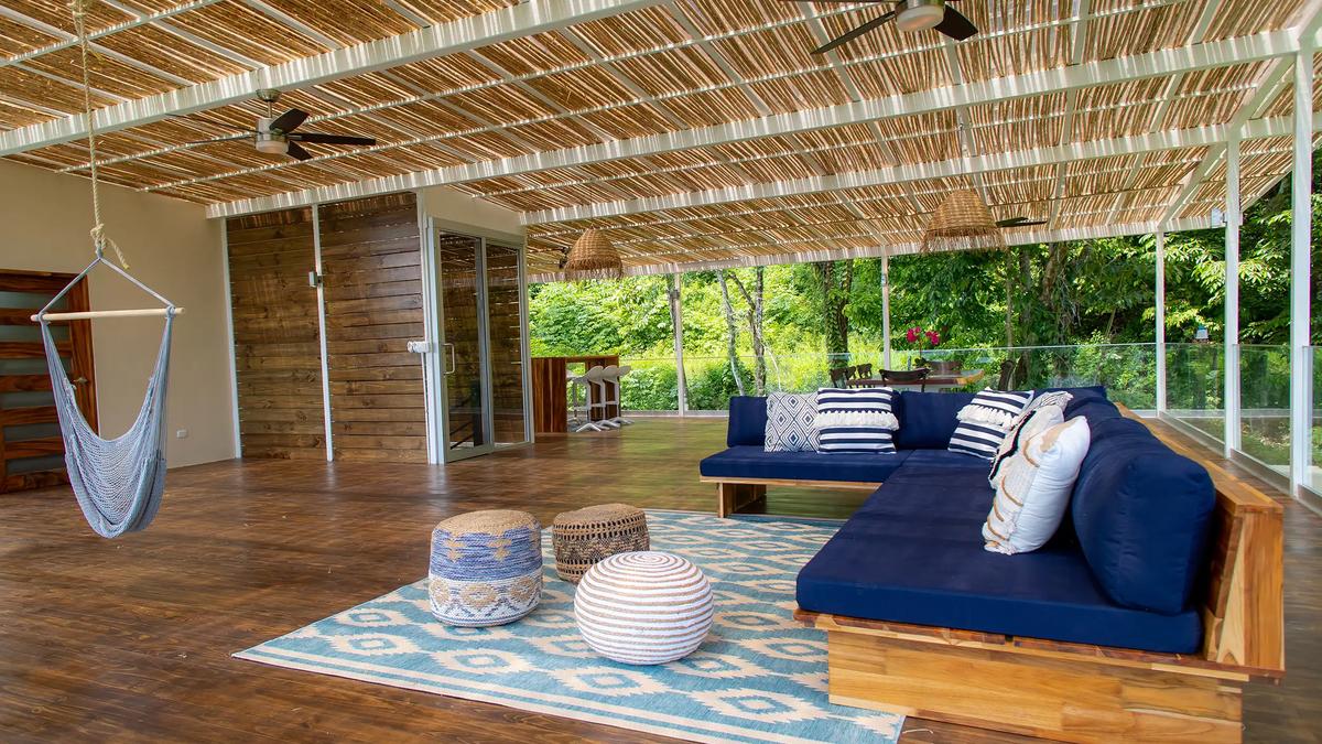 Shaded lounge at Villa Caimito with hammock chair, navy sofa, and poufs on a patterned rug