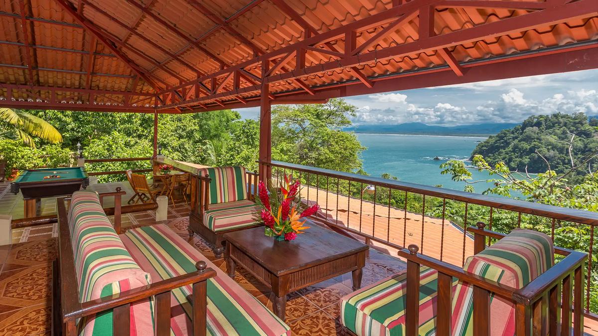 Covered rooftop terrace at Casa Pura Paz with striped seating, pool table, and ocean view