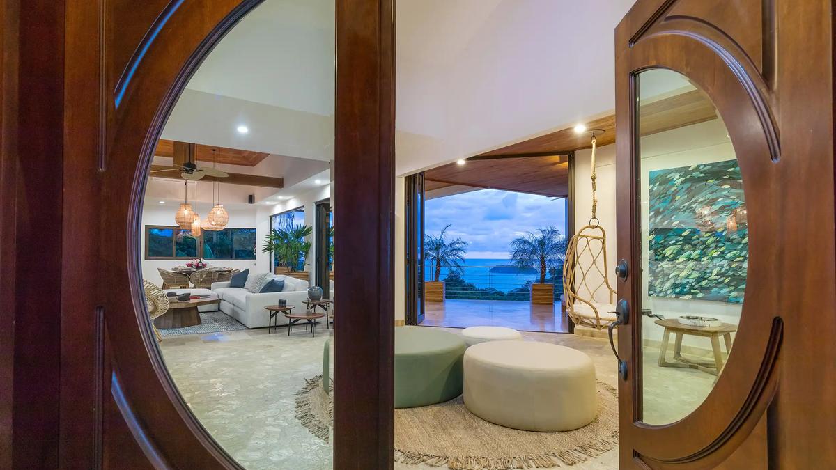 Carved wooden entry doors at Casa Anjali opening to an ocean view terrace