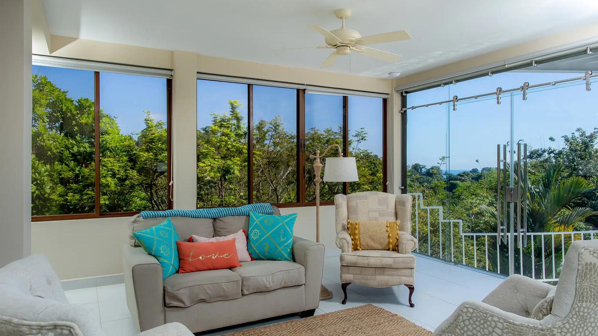 Sunroom seating corner at Casa Mariposa with treetop views through glass walls