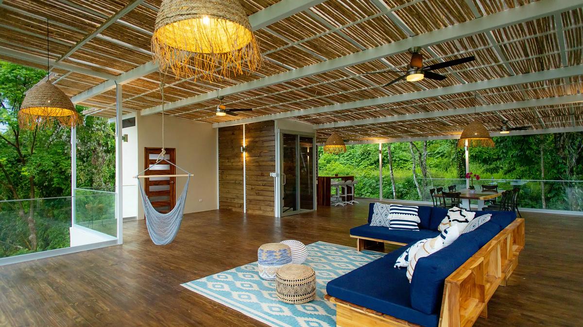 Villa Caimito's open-air living room with hammock chair, navy sectional, and woven pendant lights