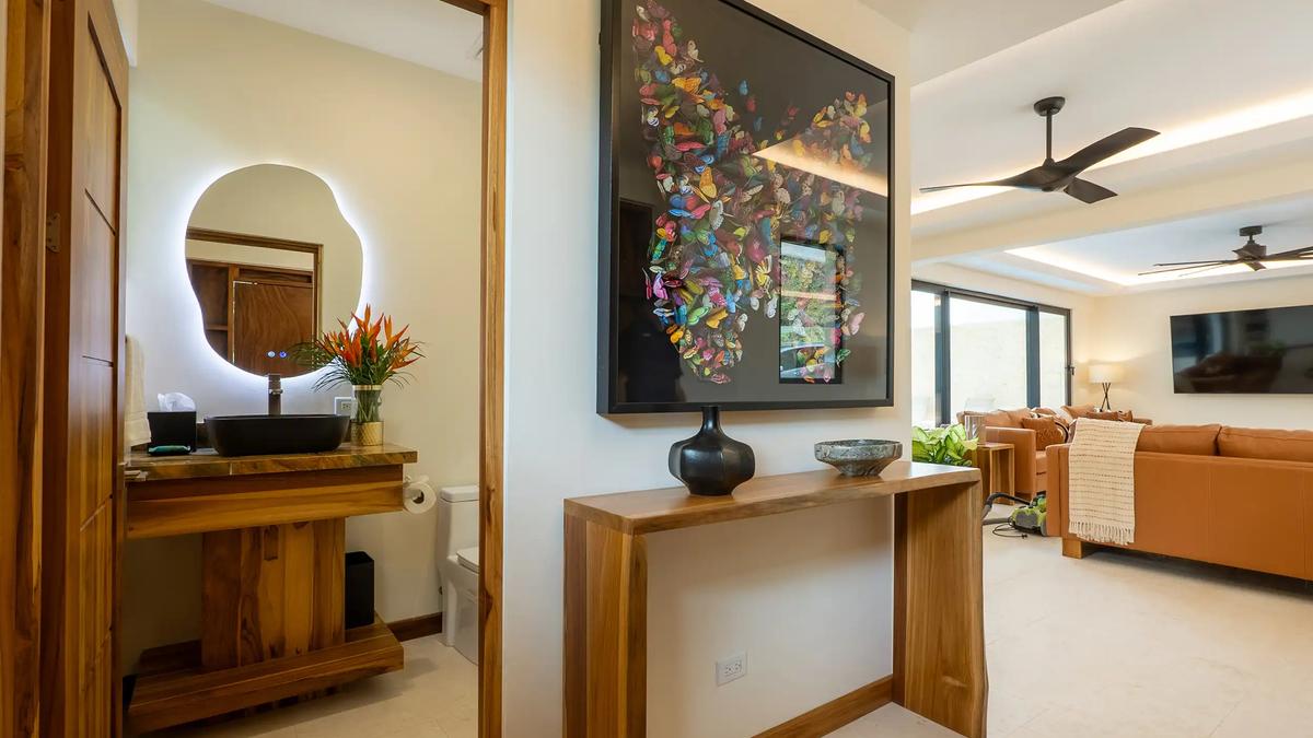 Hallway at Casa Rambutan with framed butterfly artwork, console table, and powder room