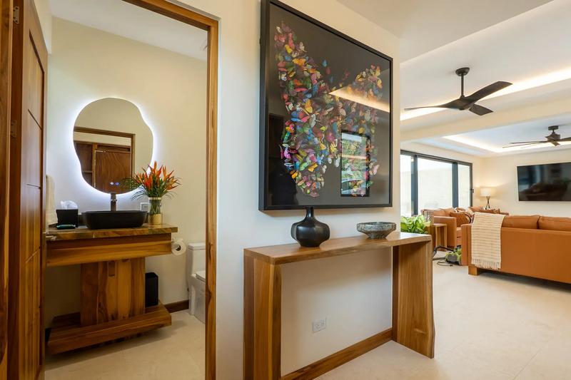 Hallway at Casa Rambutan with framed butterfly artwork, console table, and powder room