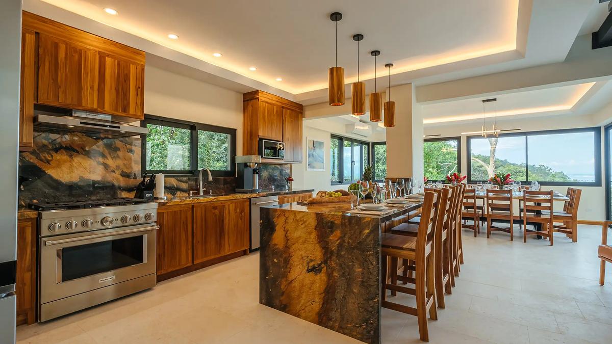 Kitchen at Casa Rambutan with granite waterfall island, teak cabinets, and bar seating