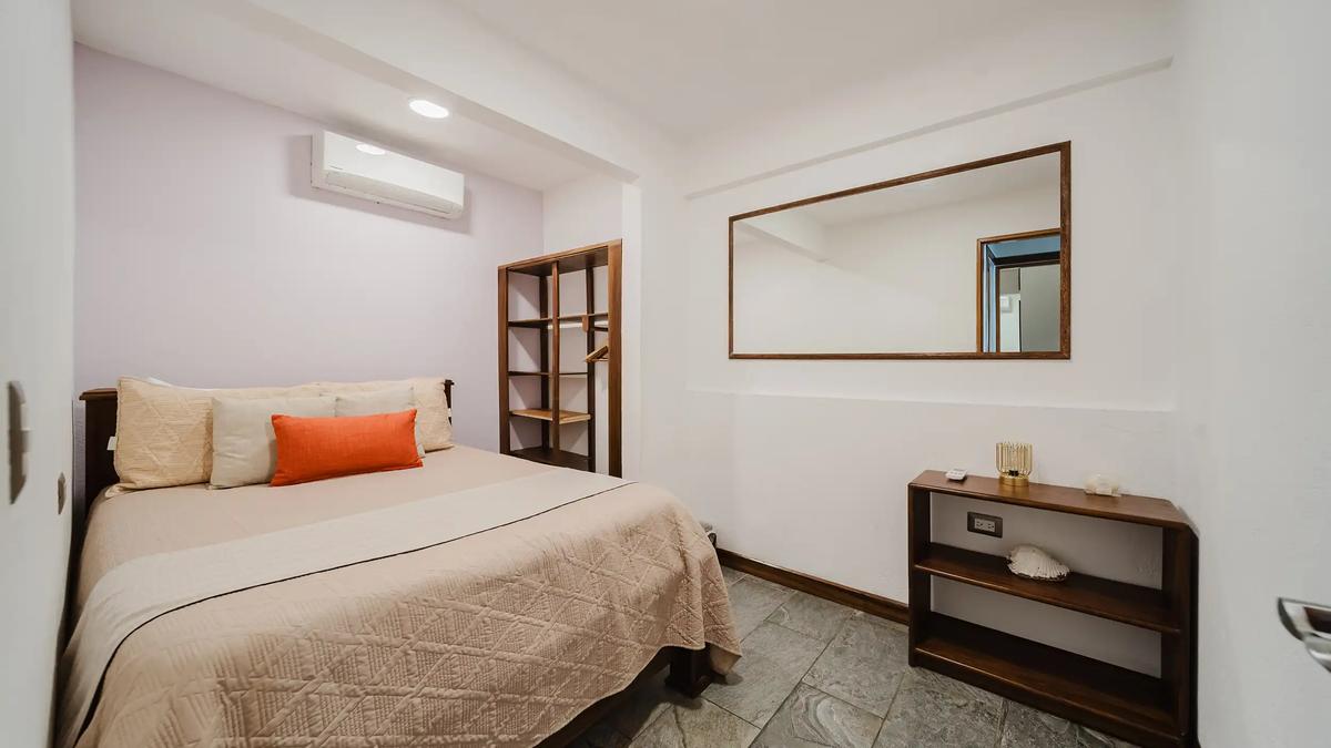 Guest bedroom at Casa Grande Vista with beige quilt and orange accent pillow