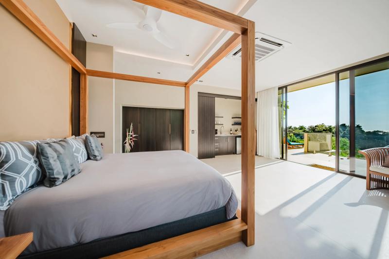 Timber four poster bed in a Casa Nola suite with sliding doors to the terrace
