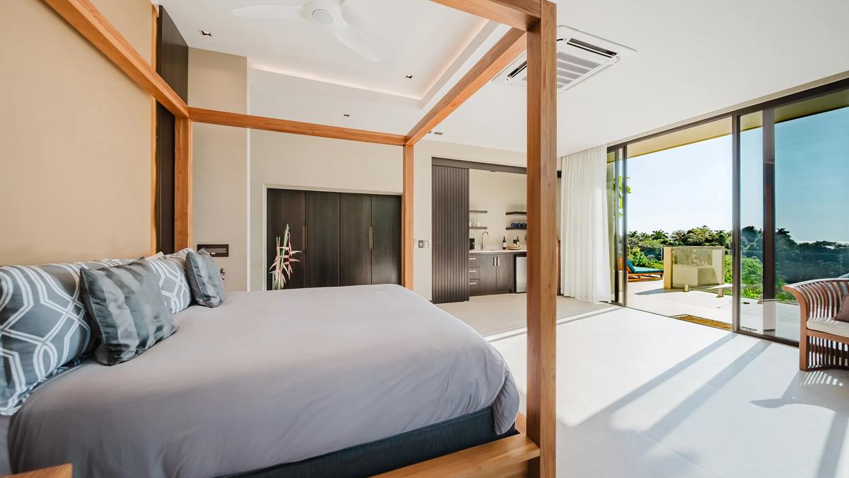 Timber four poster bed in a Casa Nola suite with sliding doors to the terrace