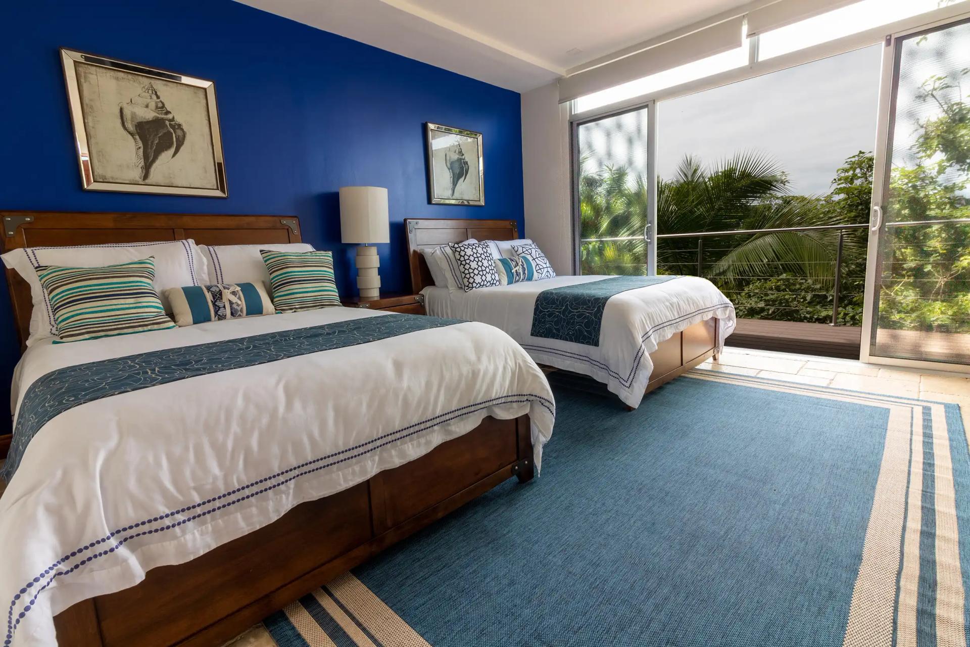 Two queen beds with blue accent wall and jungle views at Casa Contee