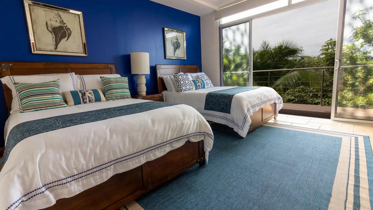 Two queen beds with blue accent wall and jungle views at Casa Contee