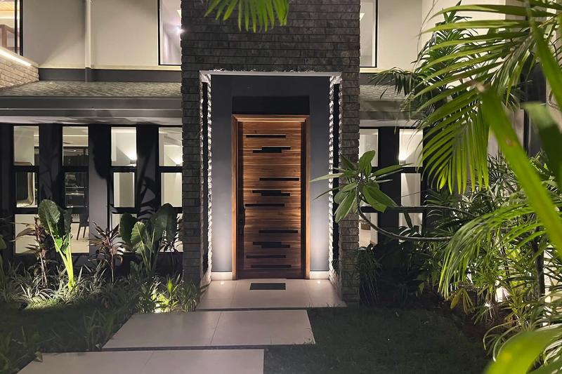 Teak entry door framed by stone pillars at Villa de Grace