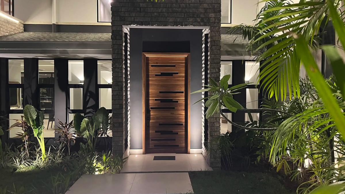 Teak entry door framed by stone pillars at Villa de Grace