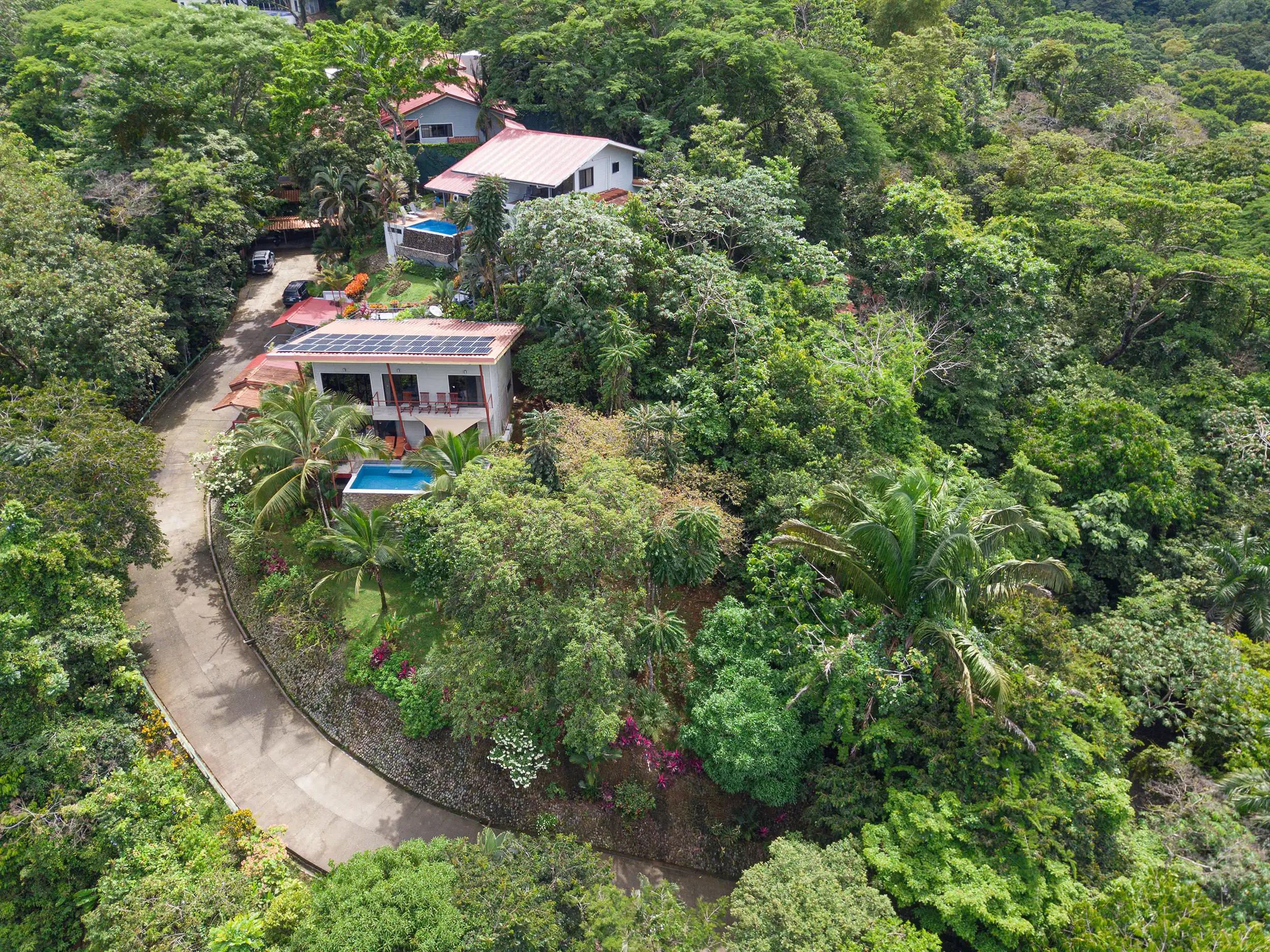 Aerial view of Casa Serenidad on a forested hillside with neighboring villas