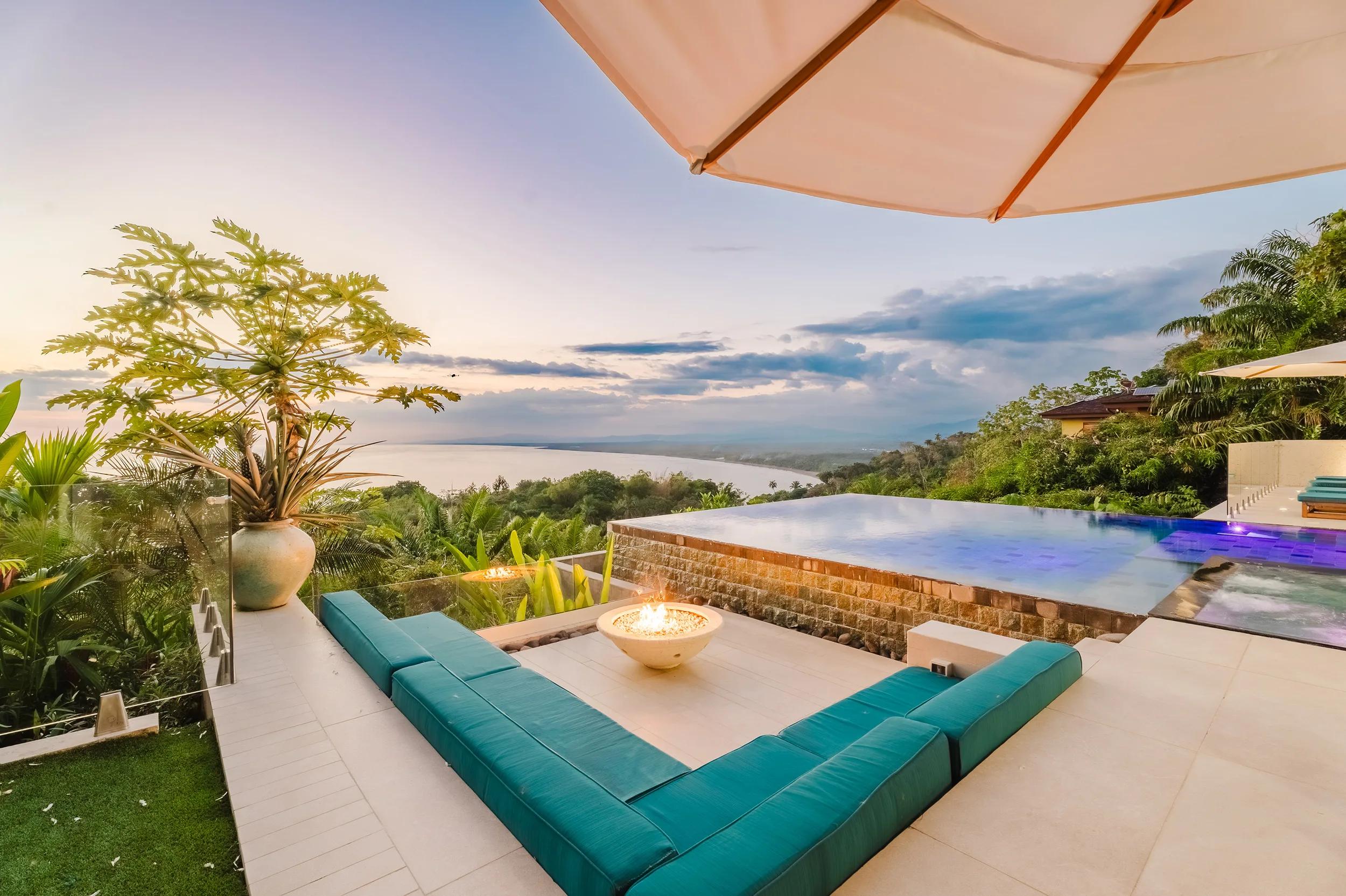Firepit lounge at Casa Nola with teal cushions and the sunset behind