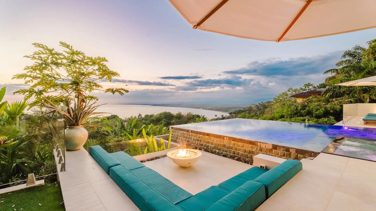 Firepit lounge at Casa Nola with teal cushions and the sunset behind