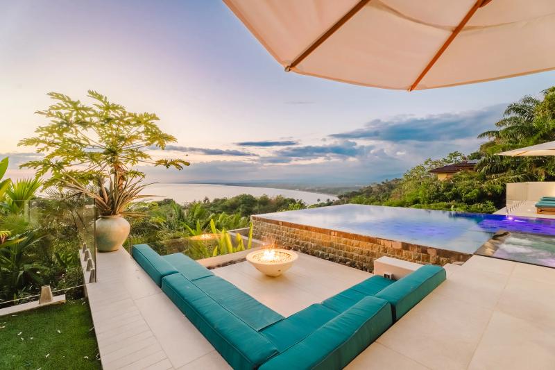 Firepit lounge at Casa Nola with teal cushions and the sunset behind