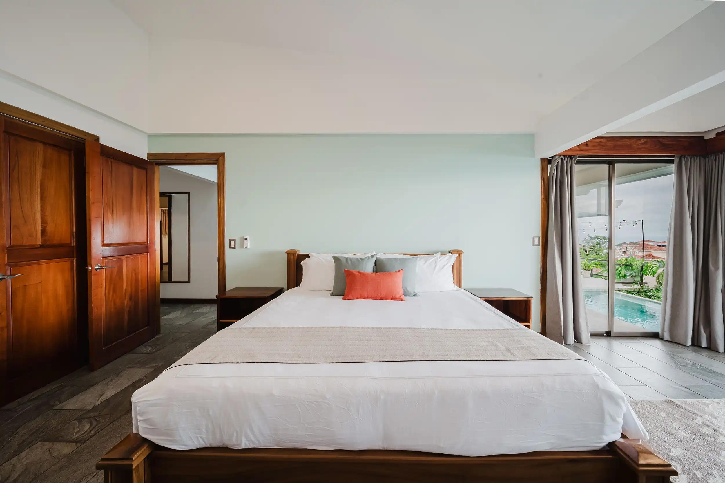 Bedroom at Casa Grande Vista with coral accent pillow and pool visible outside