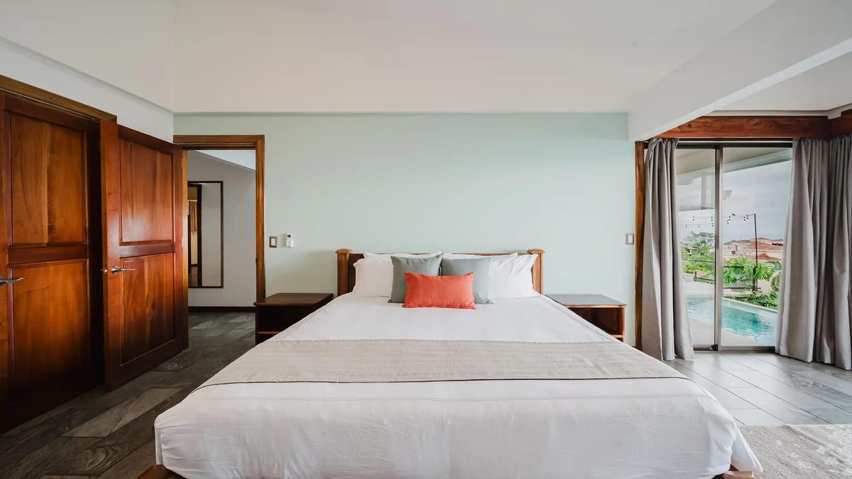 Bedroom at Casa Grande Vista with coral accent pillow and pool visible outside