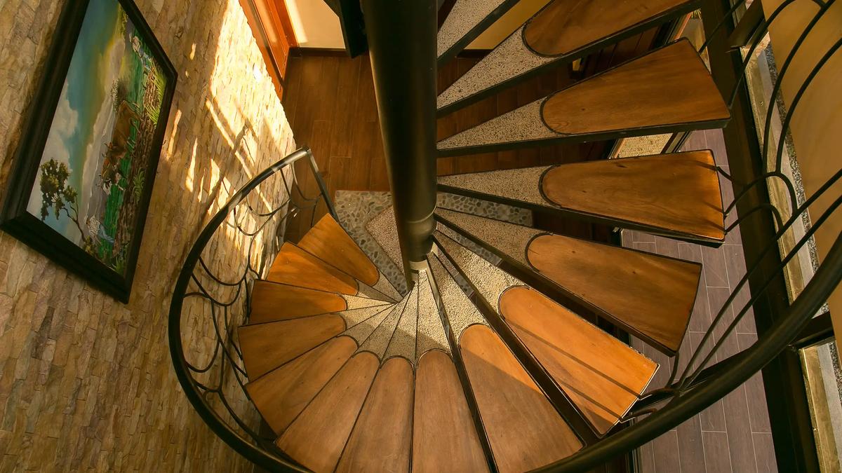 Wood and iron spiral staircase beside the stone accent wall at Casa Anaka