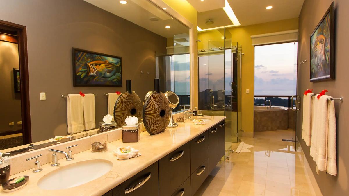 Marble double vanity in Villa Celaje's master bathroom with glass shower and sunset window