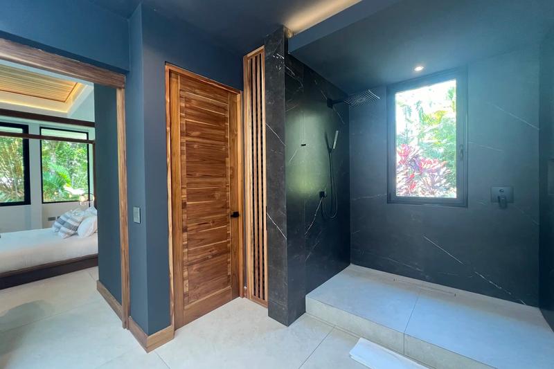 Walk in shower with black marble walls in a Villa de Grace bathroom