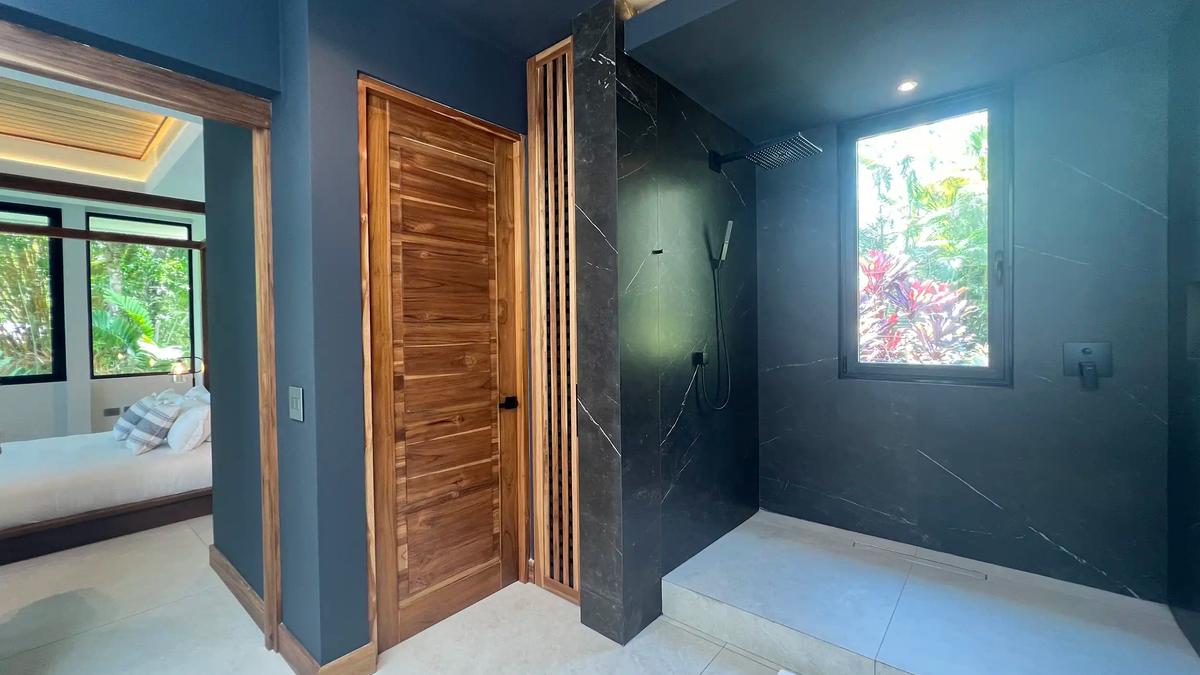 Walk in shower with black marble walls in a Villa de Grace bathroom