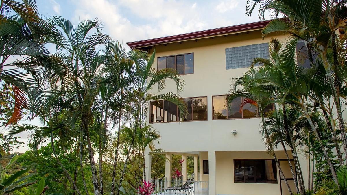 Palm trees frame the three story facade of Casa Mariposa