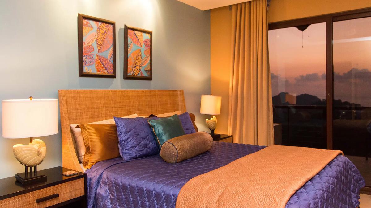 Bedroom at Villa Celaje with purple quilted bedding and a sunset glowing through the glass door