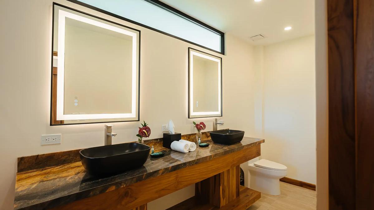 Guest bathroom at Casa Rambutan with two black vessel sinks and lighted mirrors