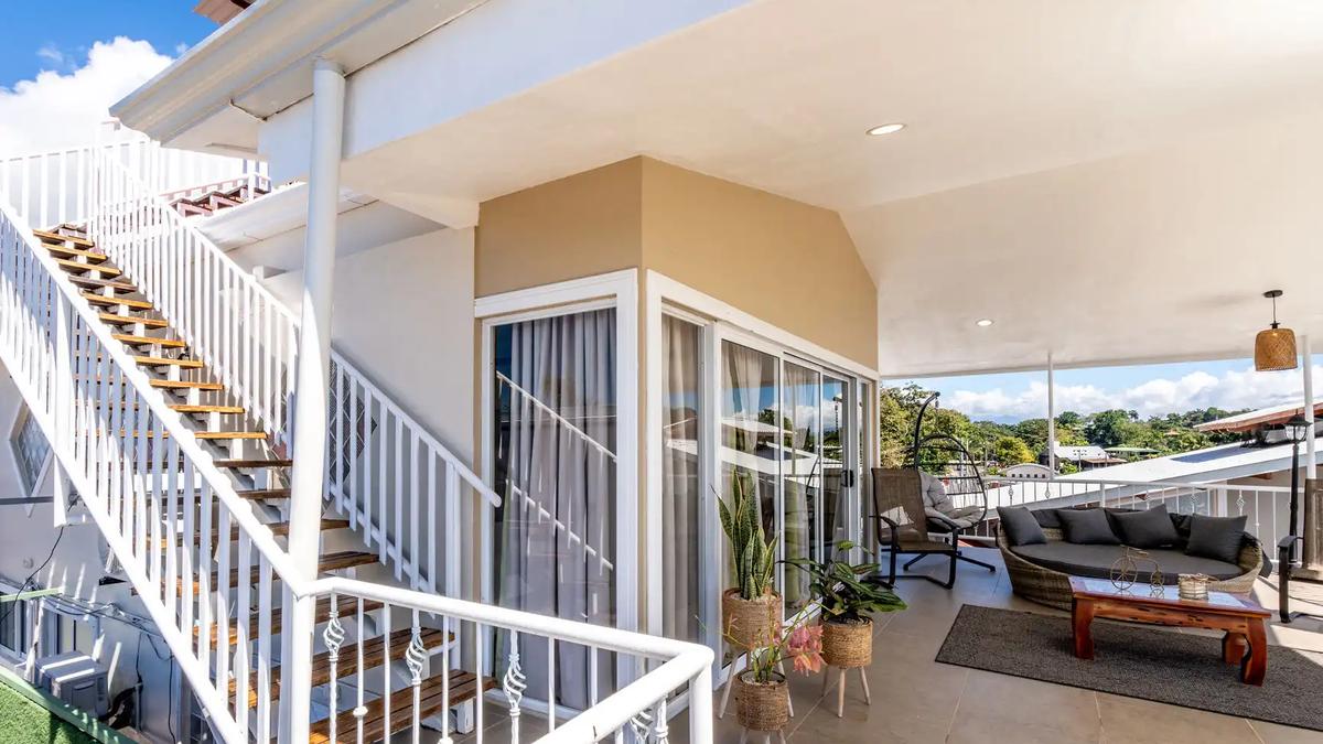 White staircase and covered terrace lounge with wicker seating at Casa Alta Vista