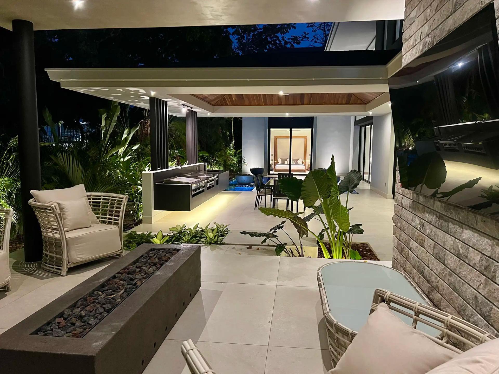 Covered terrace at Villa de Grace with lounge seating, fire pit, and outdoor kitchen