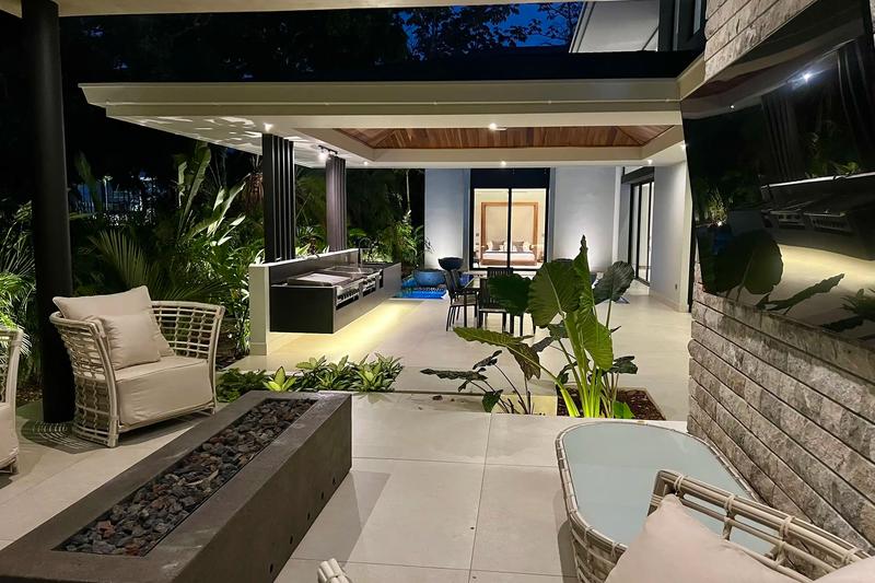 Covered terrace at Villa de Grace with lounge seating, fire pit, and outdoor kitchen