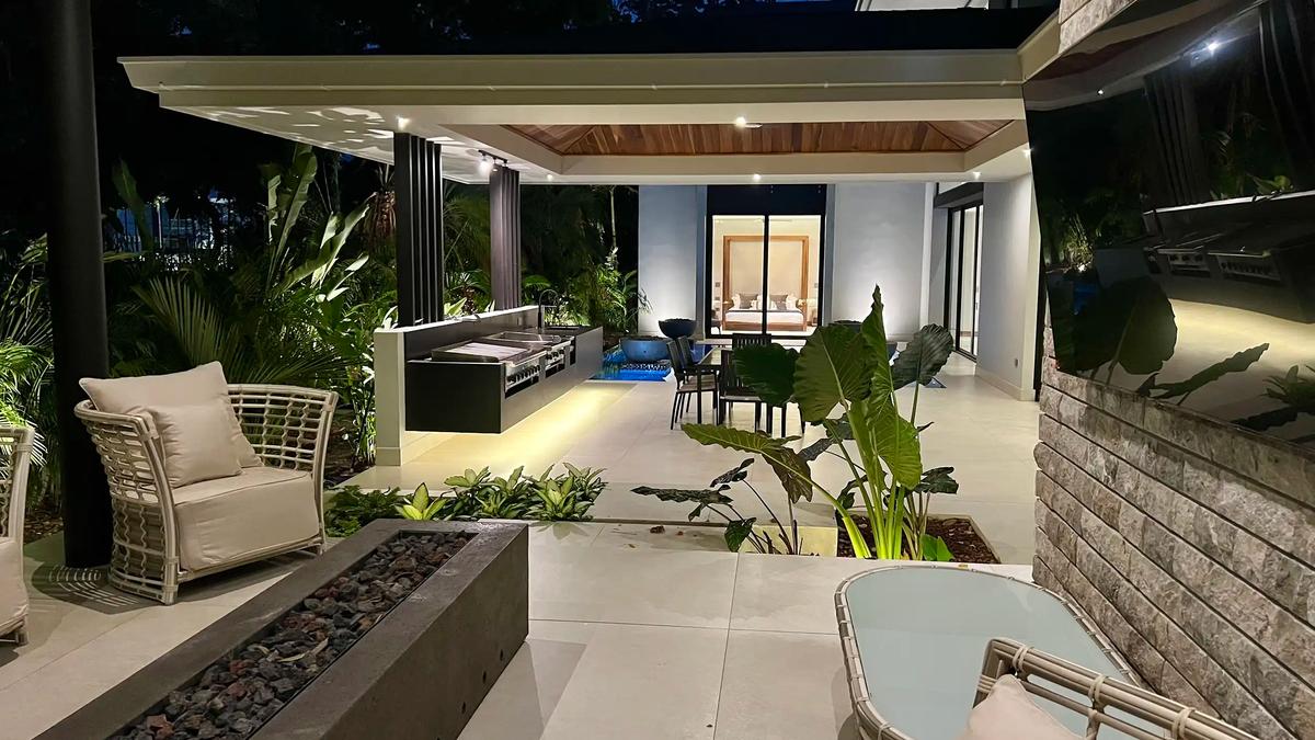 Covered terrace at Villa de Grace with lounge seating, fire pit, and outdoor kitchen