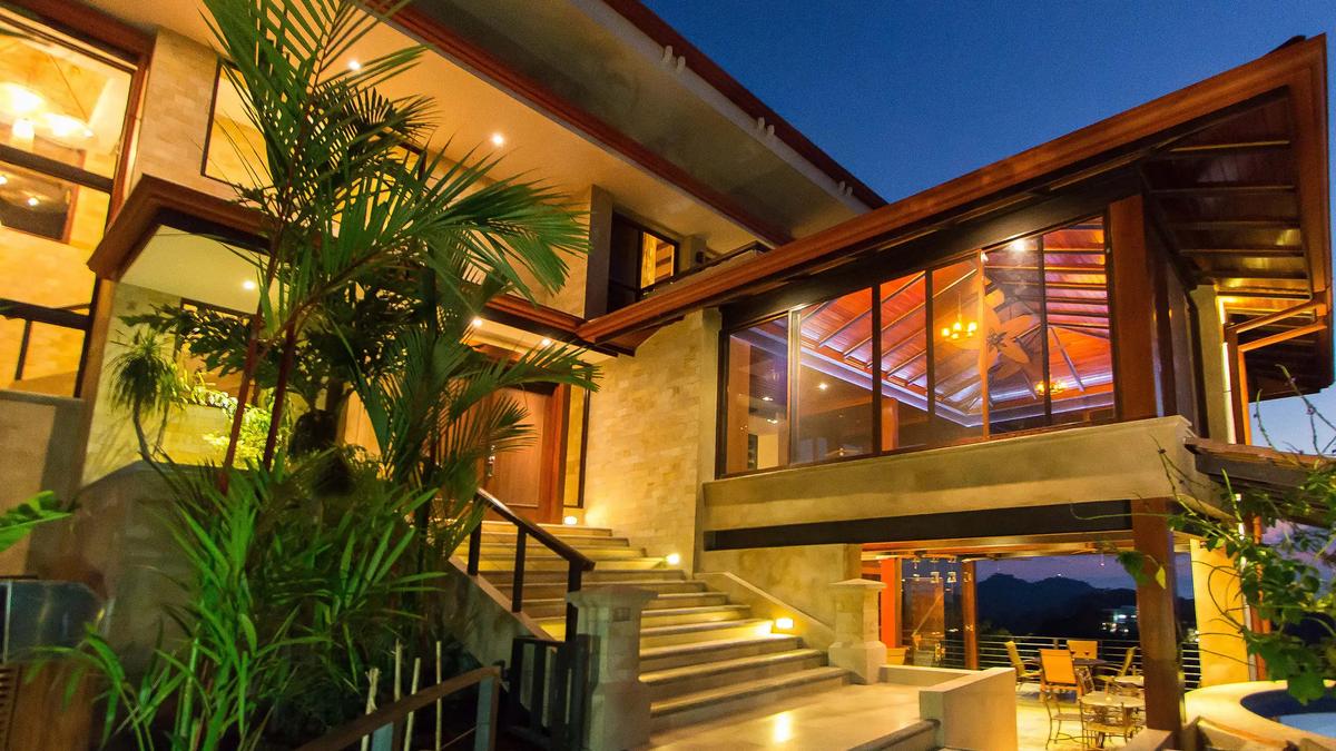 Stone entry stairway at Villa Celaje at night with the glass great room glowing above