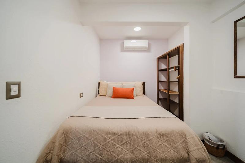 Compact guest bedroom at Casa Grande Vista with quilted bedspread and orange pillow