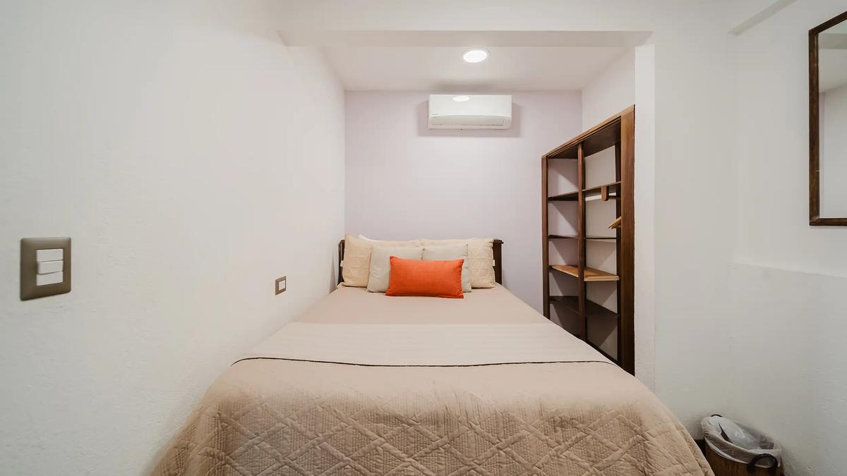 Compact guest bedroom at Casa Grande Vista with quilted bedspread and orange pillow