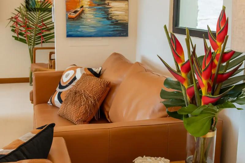 Leather sofas at Casa Rambutan with heliconia flowers and a tropical sunset painting