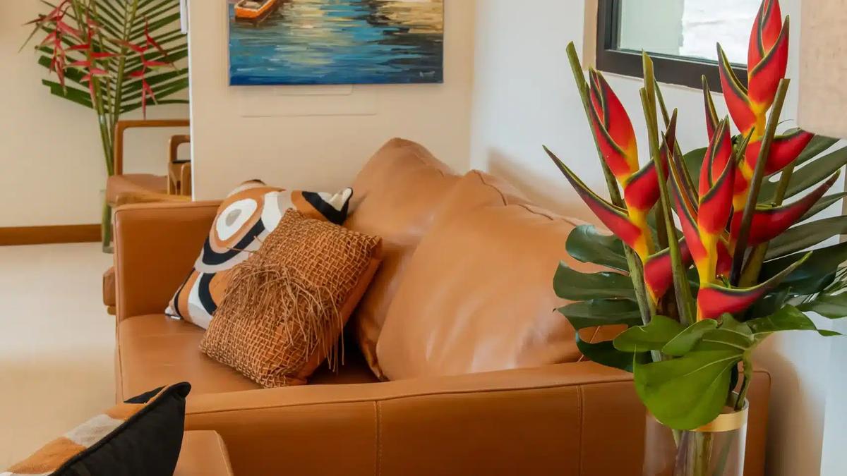 Leather sofas at Casa Rambutan with heliconia flowers and a tropical sunset painting