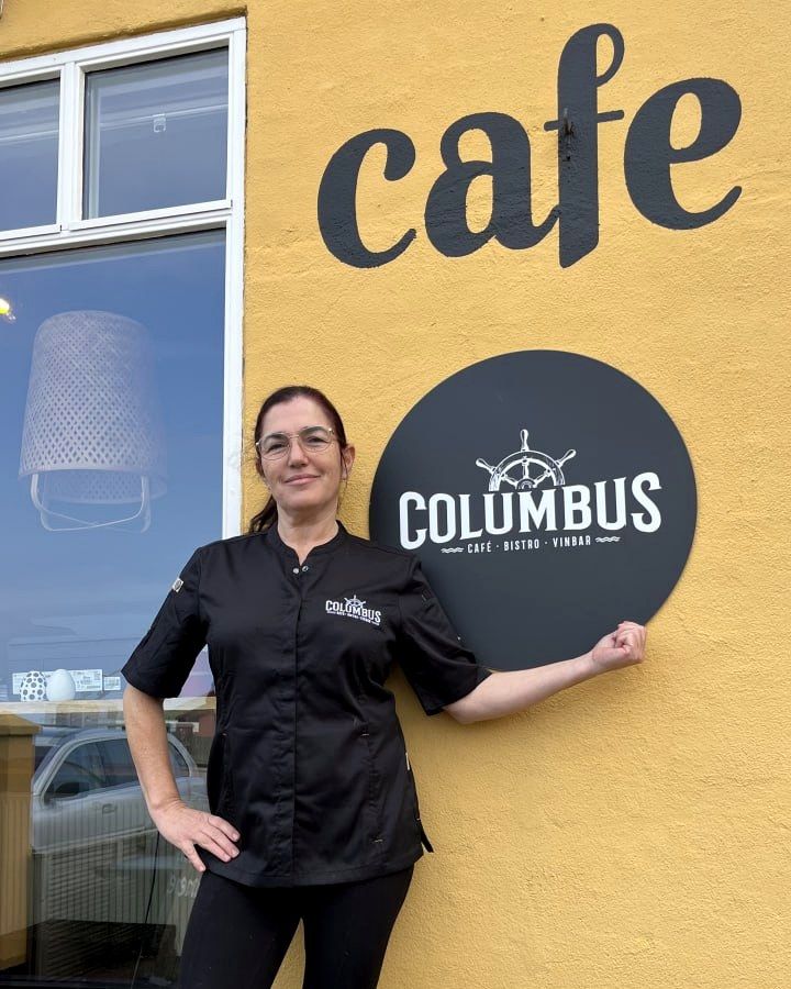 Ejeren af Café Columbus foran caféens skilt i Hundested