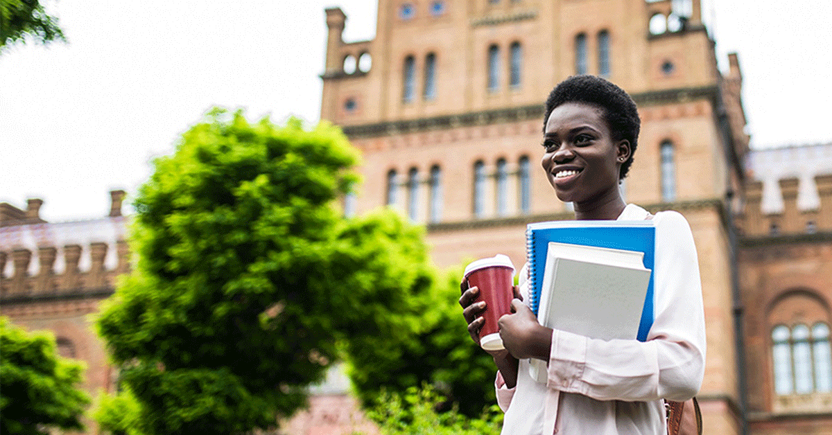 university student on campus holding books and coffee