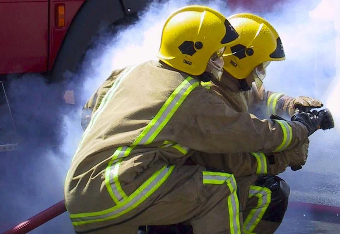A close-up of 2 firefighters holding a fire hose during training