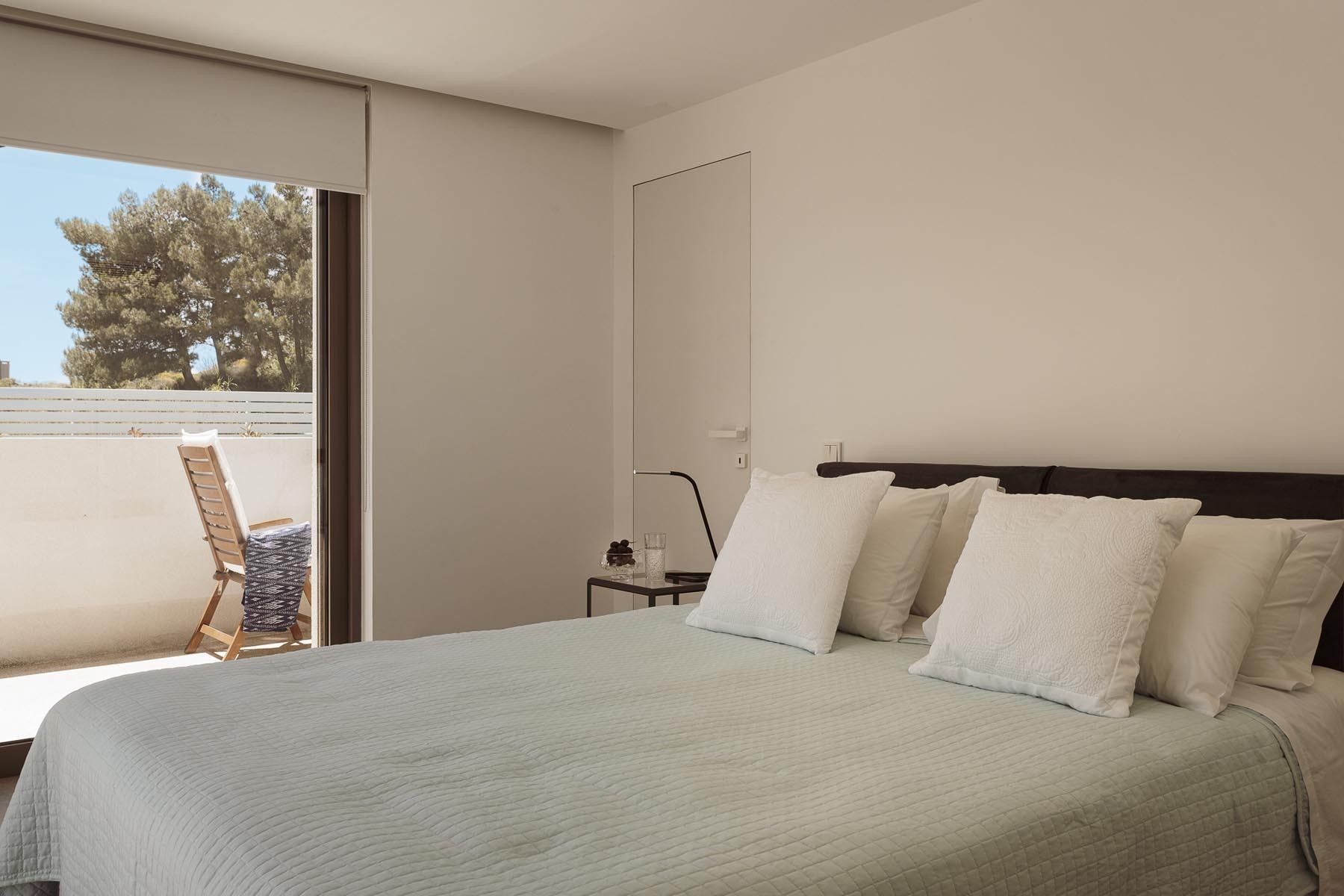 Spacious double bedroom bathed in morning sunlight with neutral decor.