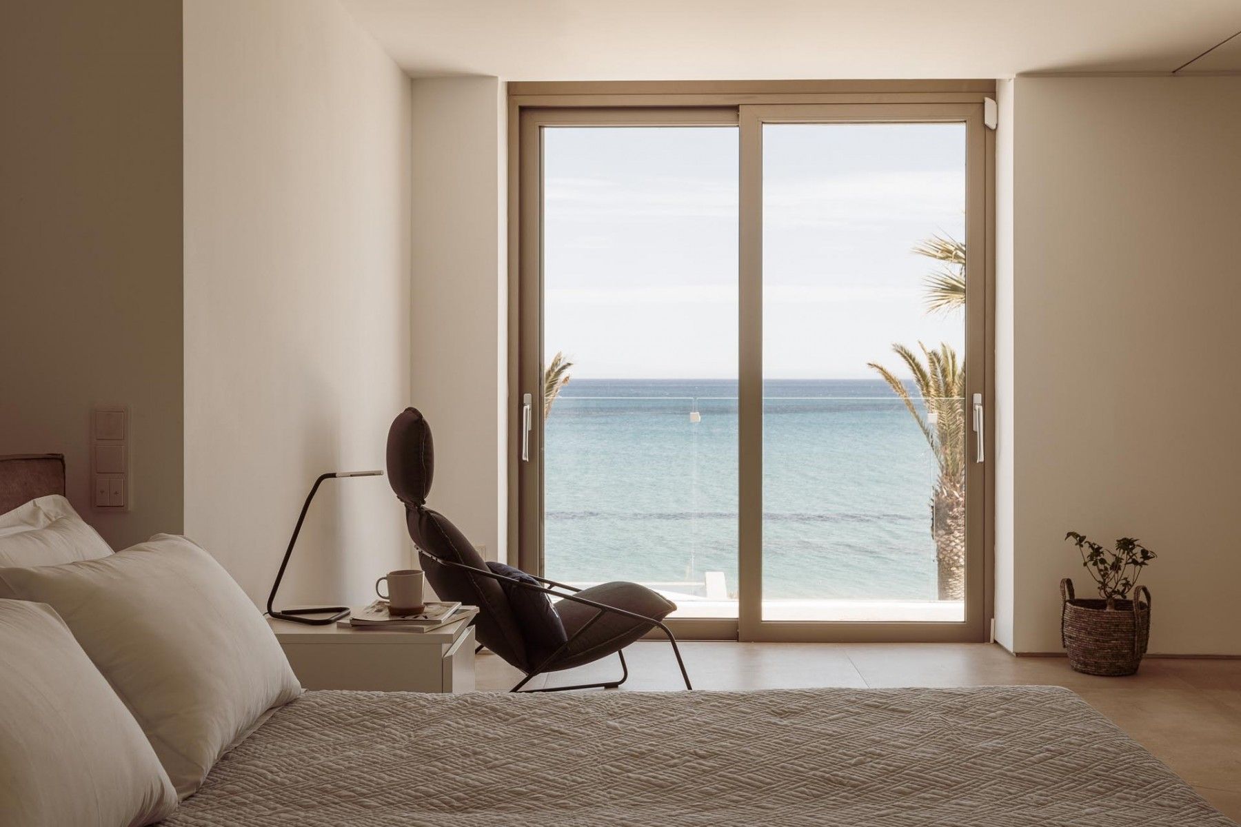 Scenic sea view from the double bed, framed by floor-to-ceiling windows.