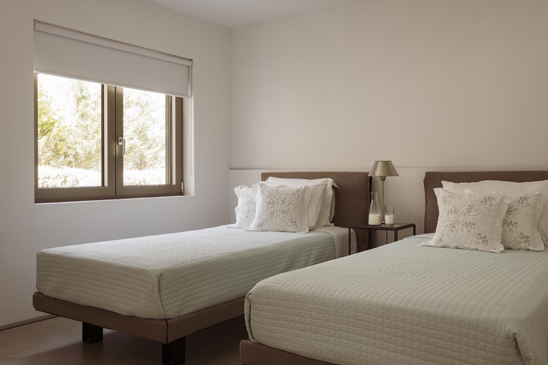 Minimalist twin-bedroom with wooden elements and warm natural light.