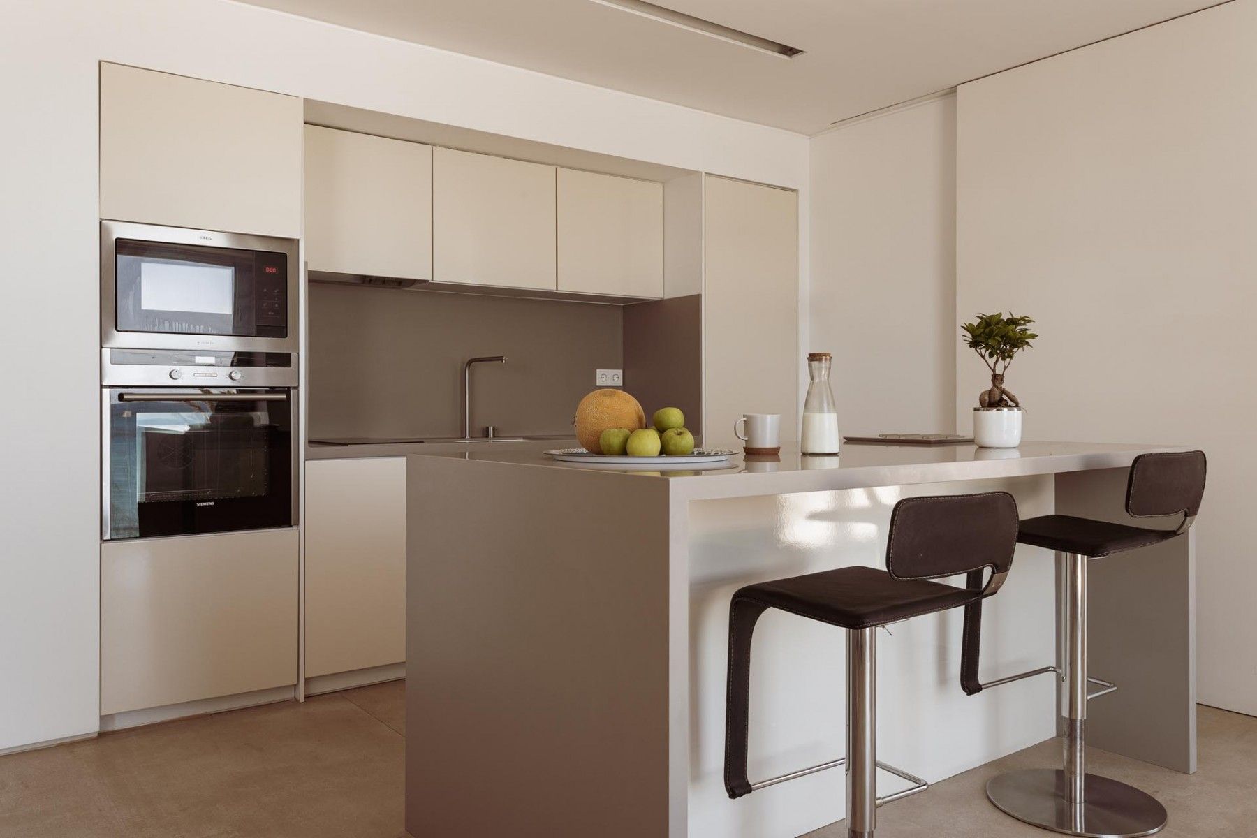 Sleek modern kitchen with a central island, barstools, and high-end appliances.