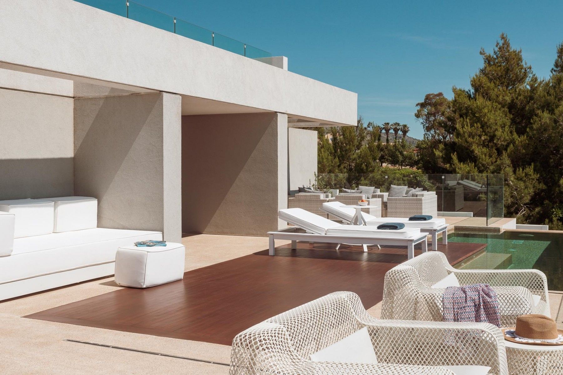 Outdoor poolside furniture illuminated by the villa’s evening lights.