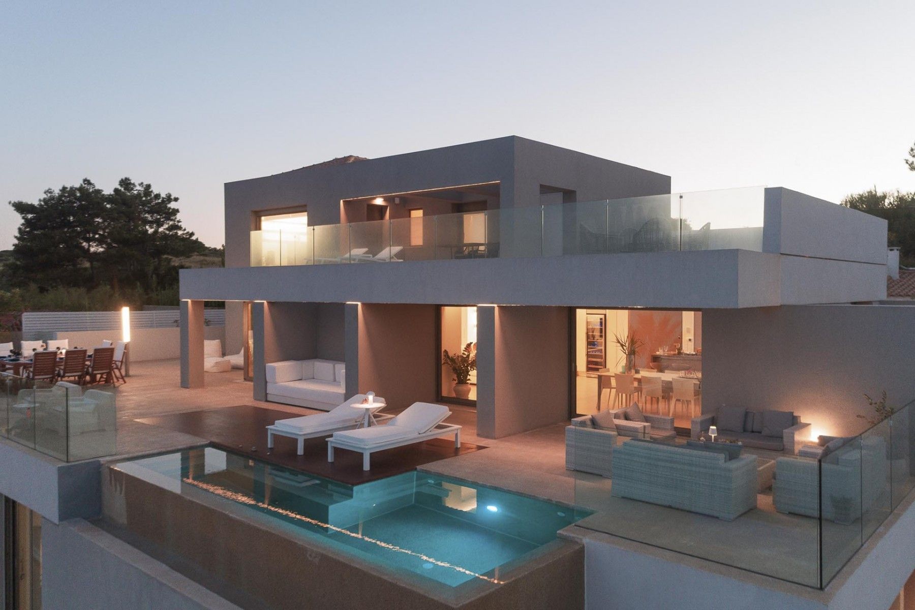 A stunning evening view of the villa’s twin pools glowing under the twilight sky.