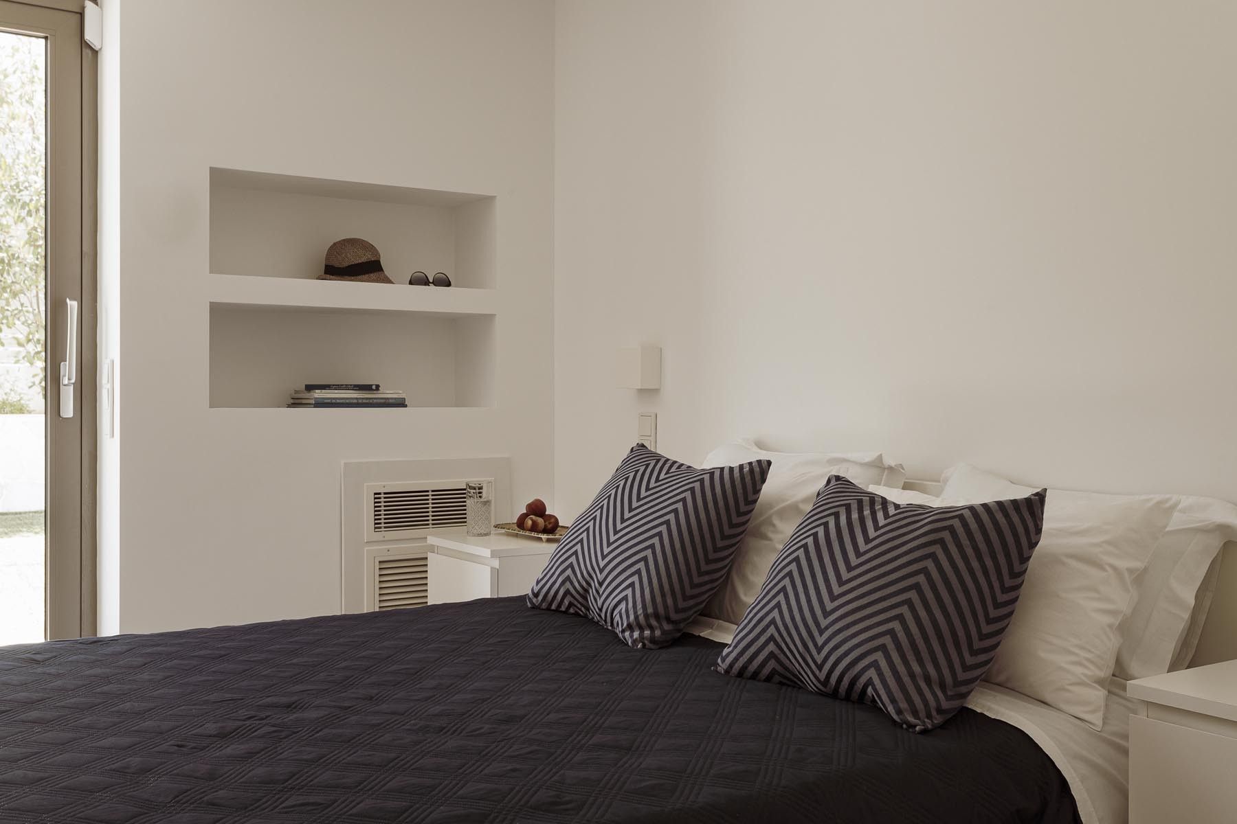 A bright and airy bedroom featuring a double bed, neutral color palette, and wooden accents.