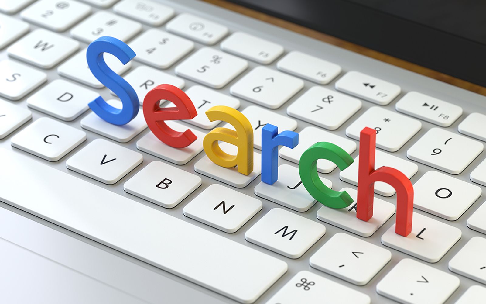 Colorful three dimensional letters spelling Search resting on a white laptop keyboard