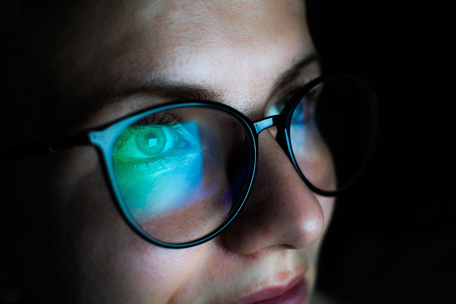 Close-up of a person in glasses with a colorful screen reflection across the lenses