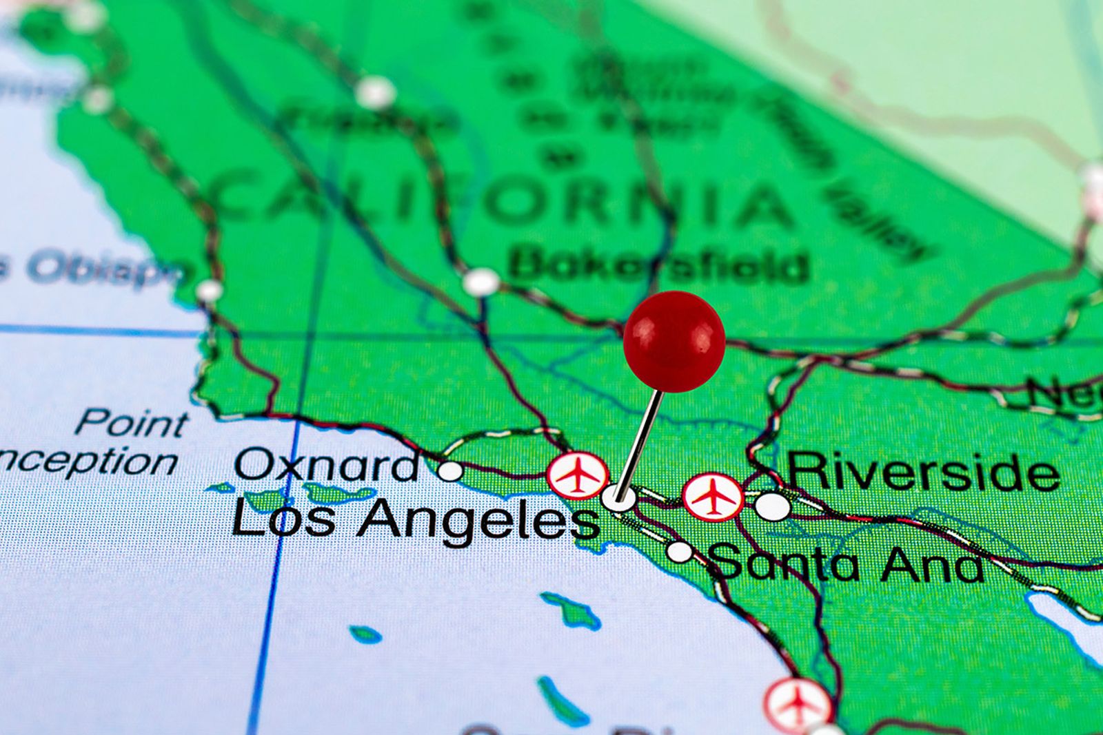 Red map pin placed on a printed regional map marking a targeted geographic boundary